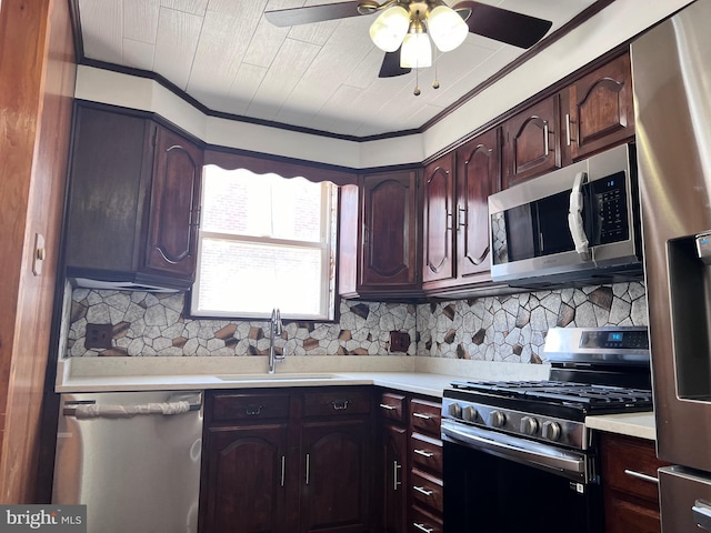 kitchen featuring appliances with stainless steel finishes, a sink, light countertops, a ceiling fan, and backsplash