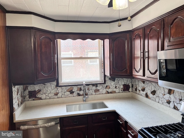 kitchen with appliances with stainless steel finishes, a sink, light countertops, dark brown cabinets, and crown molding