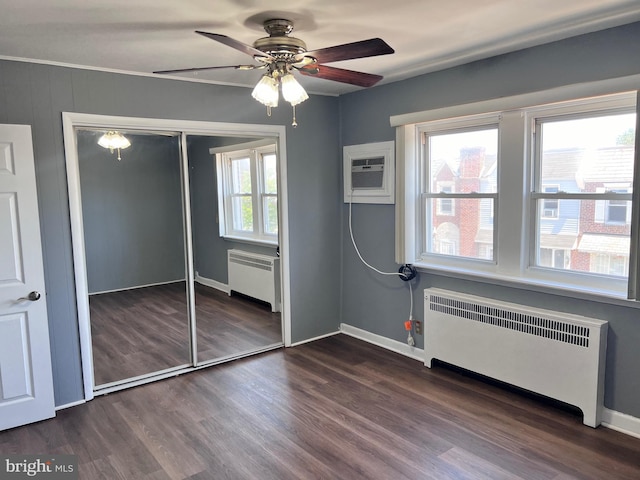 unfurnished bedroom featuring radiator, wood finished floors, a closet, and baseboards