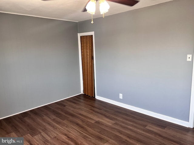unfurnished room with ceiling fan, dark wood finished floors, and baseboards
