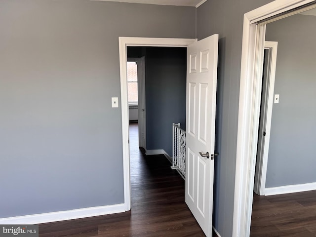 corridor featuring baseboards and dark wood-style floors