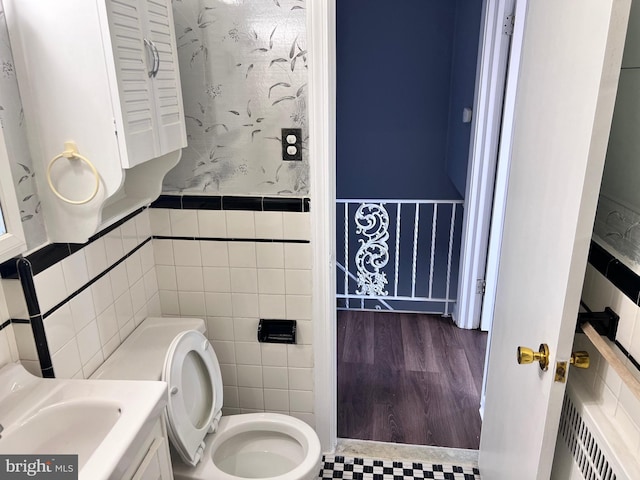 bathroom featuring tile walls, wainscoting, and toilet