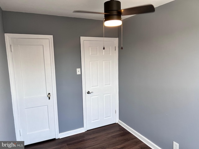 unfurnished bedroom with baseboards, dark wood-type flooring, and a ceiling fan