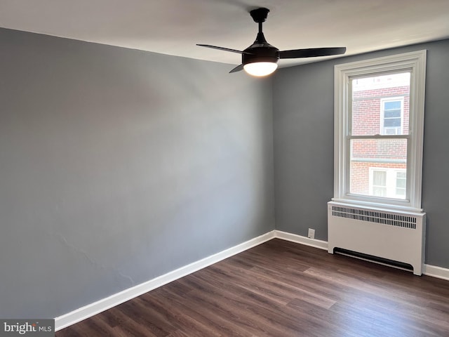 unfurnished room featuring radiator, baseboards, dark wood-type flooring, and ceiling fan