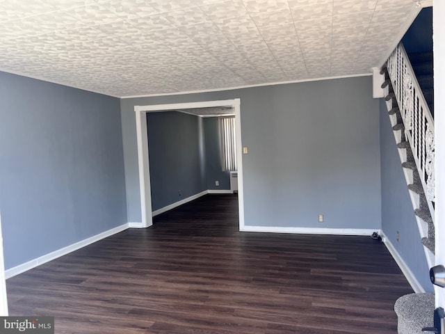 spare room with wood finished floors, baseboards, stairway, and ornamental molding