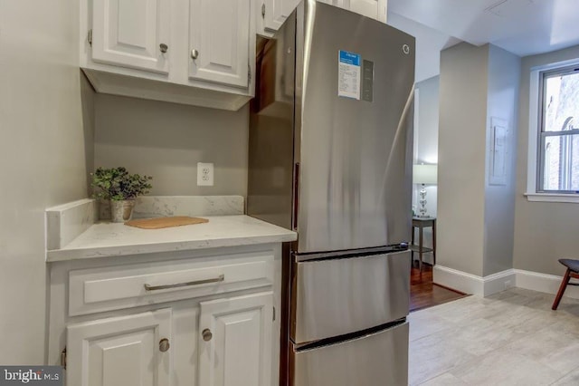 2129 Florida Ave NW Unit 507, Washington, DC 20008 - kitchen with freestanding refrigerator, white cabinets, light stone counters, and baseboards