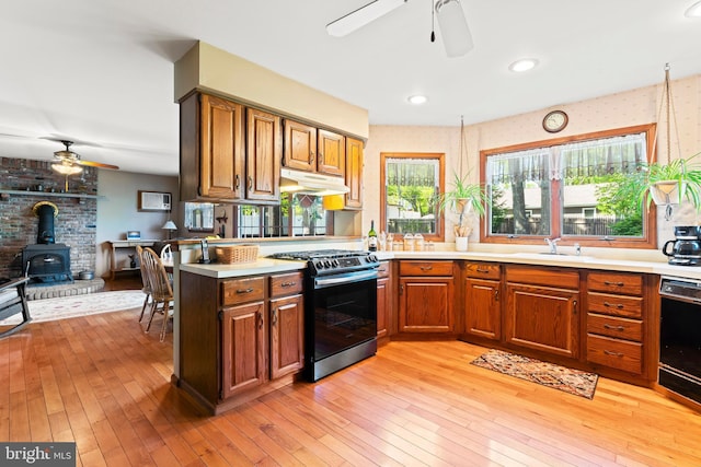 kitchen with stainless steel range with gas stovetop, a ceiling fan, a wood stove, under cabinet range hood, and recessed lighting