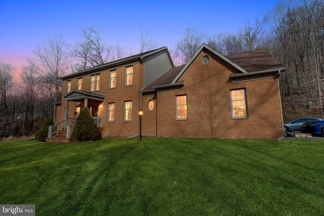 view of front of house with brick siding and a lawn