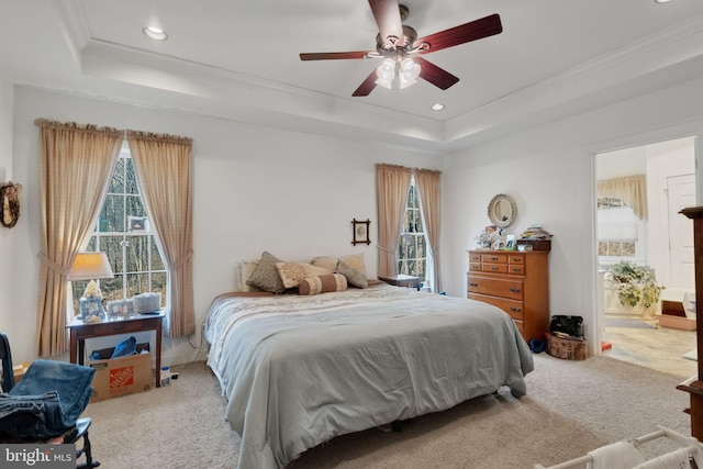 carpeted bedroom with a tray ceiling, multiple windows, ornamental molding, recessed lighting, and ensuite bathroom