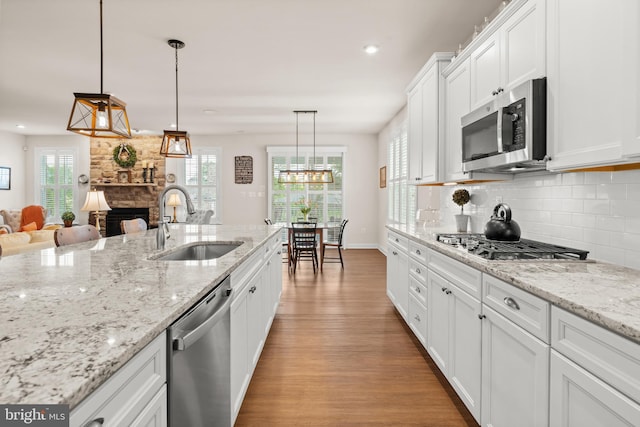 355 Dillon Cir, Middletown, DE 19709 - kitchen featuring appliances with stainless steel finishes, a sink, light wood finished floors, a fireplace, and decorative backsplash