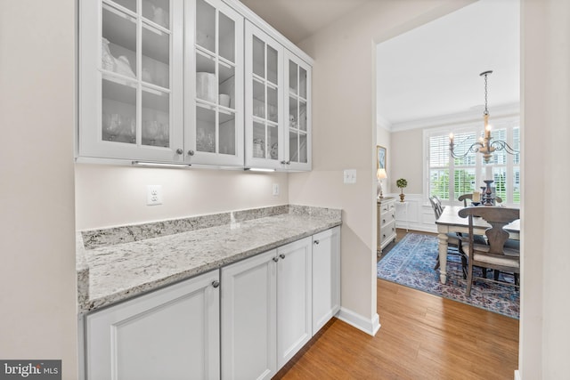 355 Dillon Cir, Middletown, DE 19709 - kitchen with light wood-style floors, white cabinetry, glass insert cabinets, a chandelier, and ornamental molding