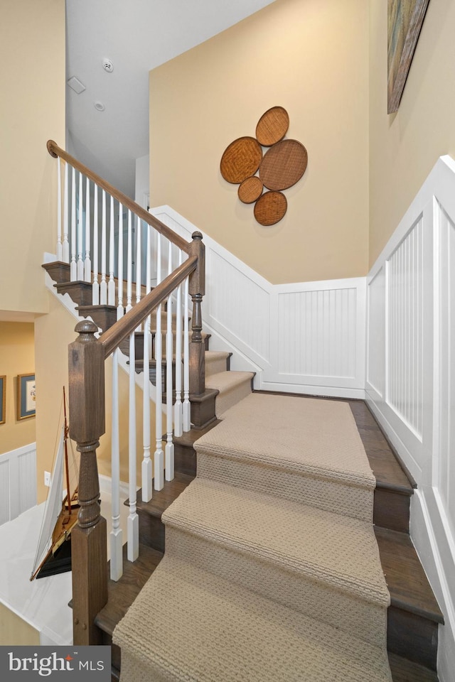 355 Dillon Cir, Middletown, DE 19709 - staircase featuring wood finished floors, a decorative wall, a wainscoted wall, and a towering ceiling