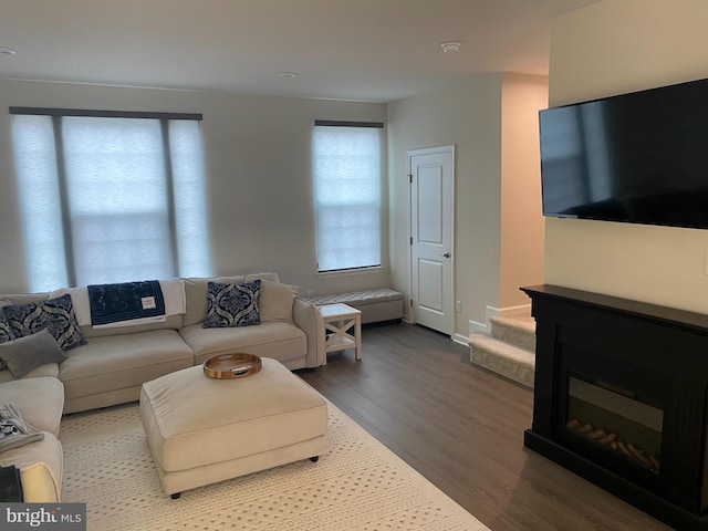 living room featuring wood finished floors, stairs, and baseboards