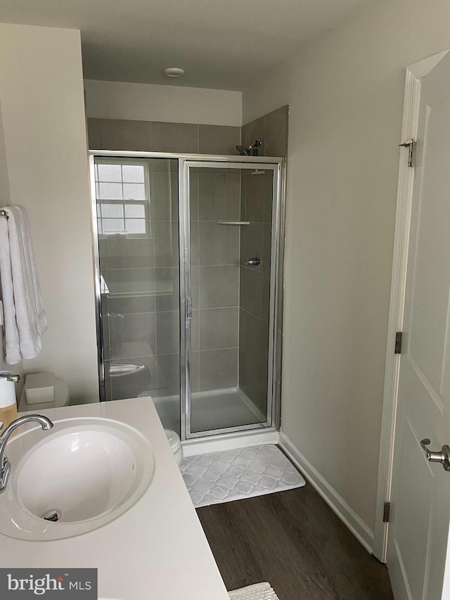 full bathroom featuring a stall shower, wood finished floors, toilet, and vanity