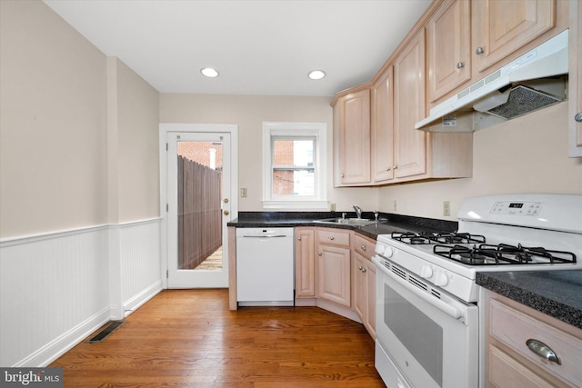 1718 N Scott St, Wilmington, DE 19806 - kitchen with white appliances, under cabinet range hood, light brown cabinets, a sink, and a wainscoted wall