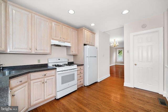 1718 N Scott St, Wilmington, DE 19806 - kitchen with white appliances, under cabinet range hood, a chandelier, light wood-style floors, and dark countertops