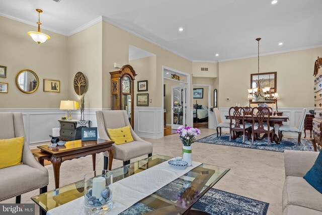 living area featuring a decorative wall, recessed lighting, ornamental molding, a chandelier, and wainscoting