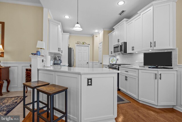 kitchen featuring stainless steel appliances, white cabinets, recessed lighting, crown molding, and a breakfast bar