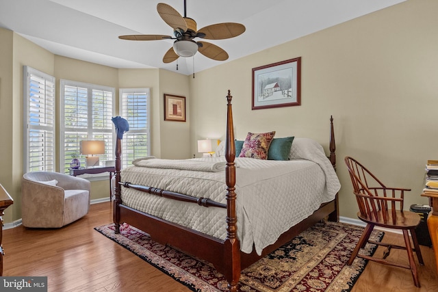 bedroom featuring baseboards, wood finished floors, and a ceiling fan