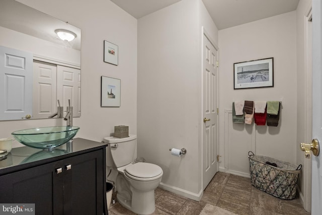 bathroom with toilet, vanity, and baseboards