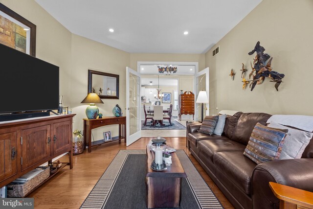 living room featuring light wood-type flooring, baseboards, a chandelier, and recessed lighting