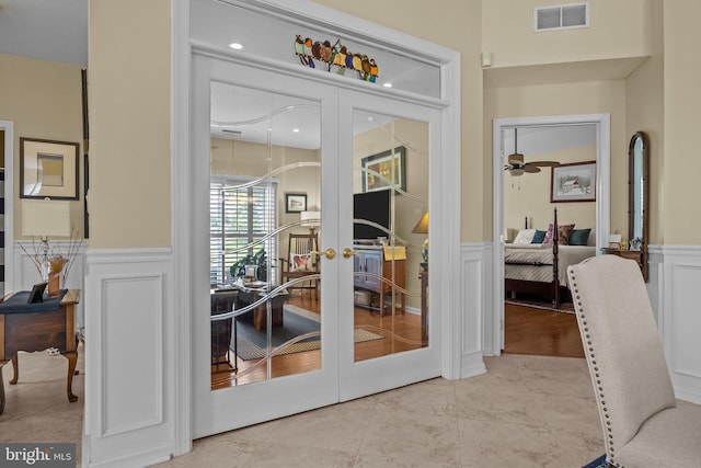 doorway to outside featuring french doors, a decorative wall, wainscoting, and tile patterned flooring