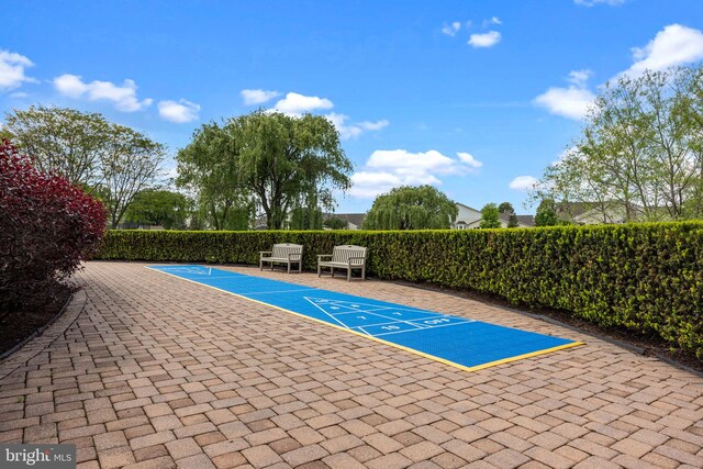 view of pool with shuffleboard and fence