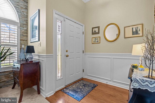 entryway with a decorative wall, wainscoting, and wood finished floors