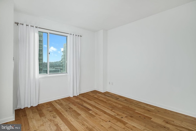 unfurnished room featuring light wood finished floors and baseboards