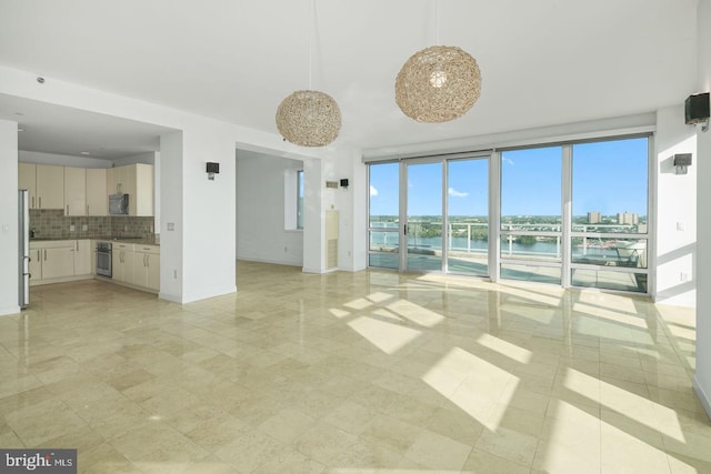 unfurnished living room featuring a water view and baseboards