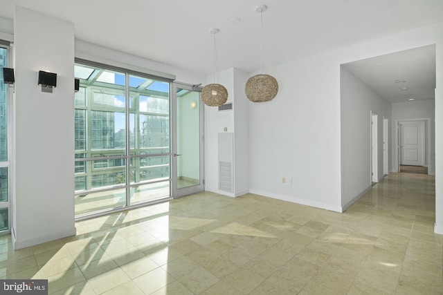 spare room featuring light tile patterned flooring and baseboards