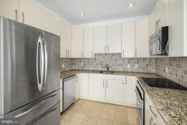 kitchen with appliances with stainless steel finishes, a sink, decorative backsplash, light stone countertops, and recessed lighting
