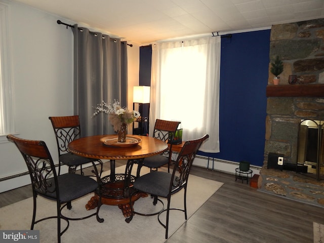 dining space with wood finished floors, baseboards, and a baseboard radiator