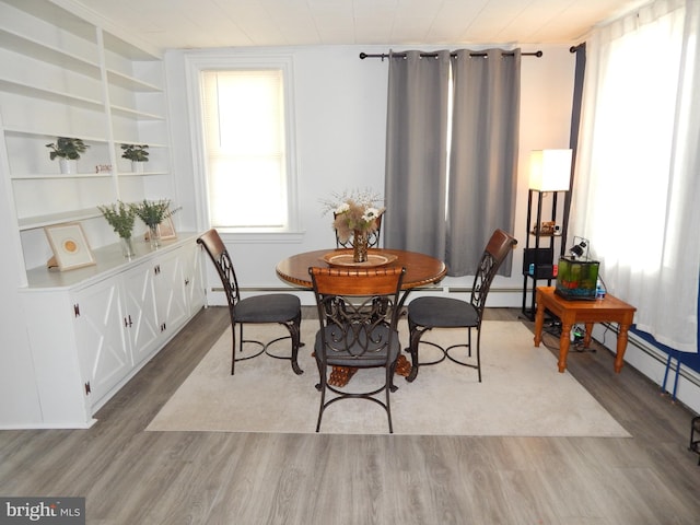 dining space featuring wood finished floors and a baseboard radiator