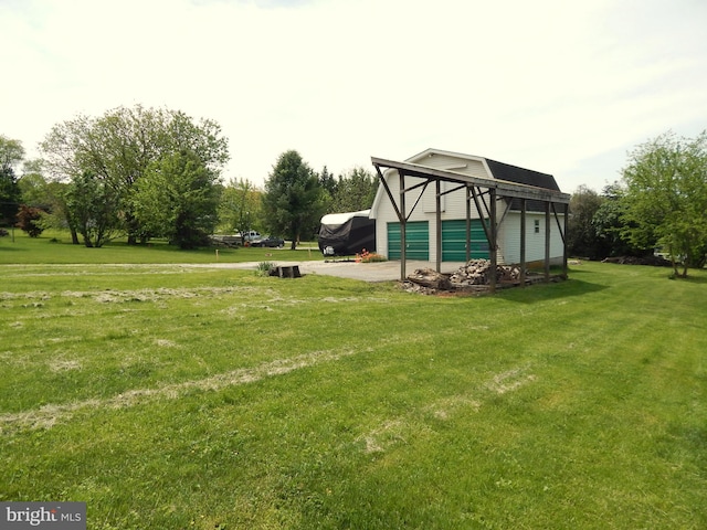 view of grassy yard featuring an outdoor structure, driveway, and a garage