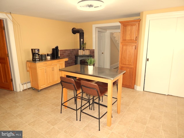 dining room featuring a baseboard heating unit, a wood stove, and stairway