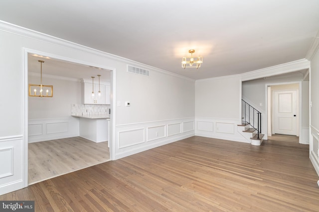 203 Shenandoah Rd, Cinnaminson, NJ 08077 - empty room with a chandelier, a decorative wall, wood finished floors, stairway, and ornamental molding