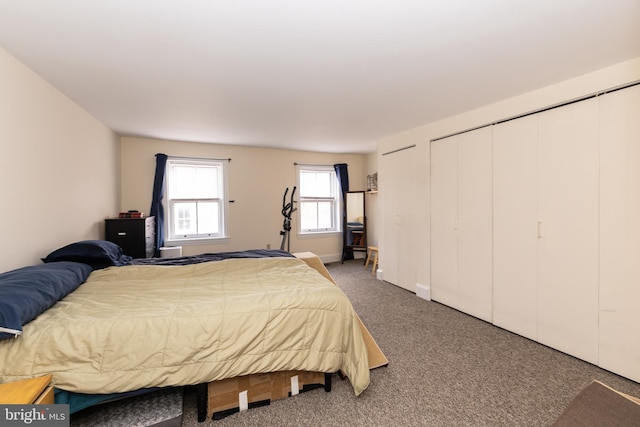 carpeted bedroom featuring two closets and baseboards