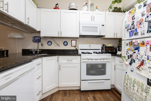 kitchen featuring white appliances, a sink, white cabinetry, dark wood-style flooring, and dark stone counters