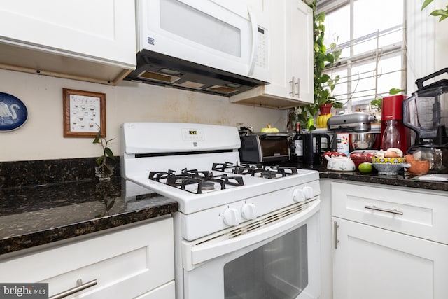 kitchen featuring white appliances, white cabinetry, and dark stone countertops