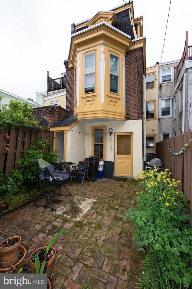 rear view of property featuring fence, a patio, and stucco siding