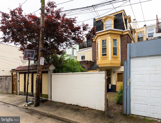 view of front of home featuring fence, mansard roof, and brick siding