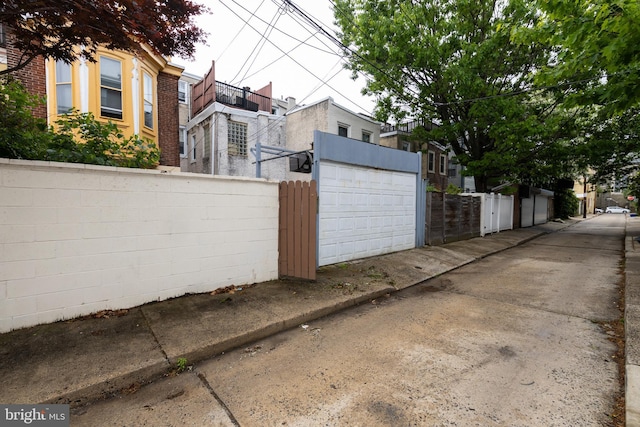 view of side of property featuring fence, a garage, and brick siding