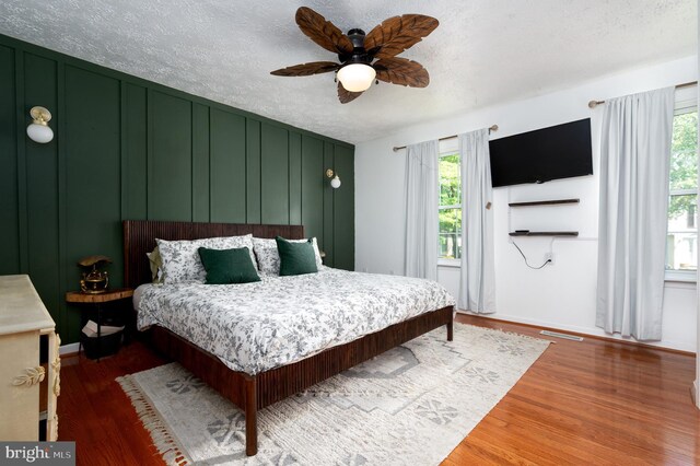 4783 Jaybird Ct, Waldorf, MD 20603 - bedroom featuring wood finished floors, a textured ceiling, baseboards, ceiling fan, and a decorative wall