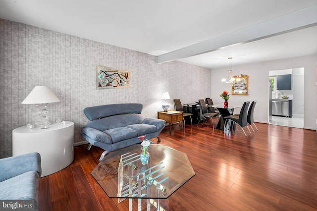 living room featuring wallpapered walls, a chandelier, wood finished floors, and an accent wall