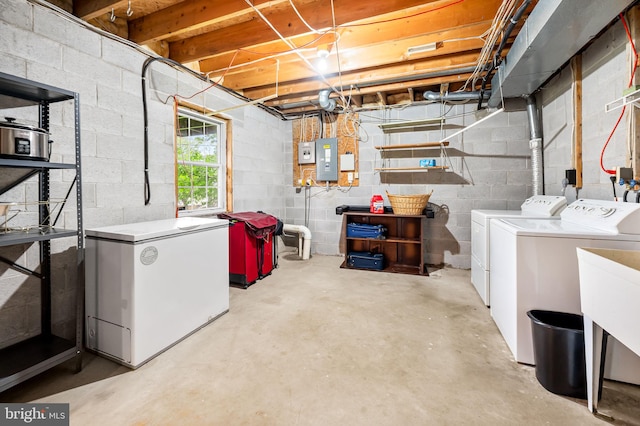 below grade area with washing machine and dryer, refrigerator, electric panel, and concrete block wall