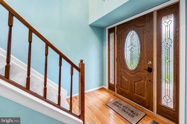 entryway with light wood finished floors, stairs, and baseboards