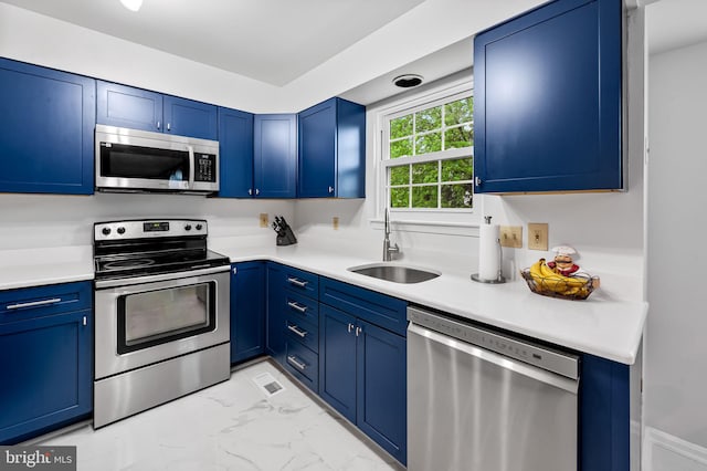 kitchen featuring stainless steel appliances, a sink, blue cabinetry, and light marble finish floors