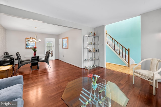 living area featuring stairway, a chandelier, wood finished floors, and baseboards