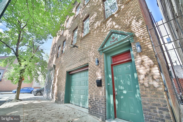 entrance to property featuring brick siding and a garage